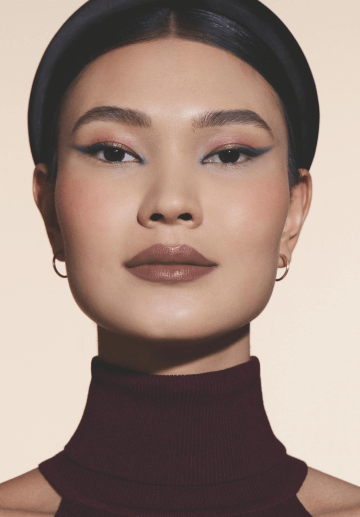 Mulher com cabelo escuro e tiara na cabeça com sombra nos olhos e blush nas bochechas